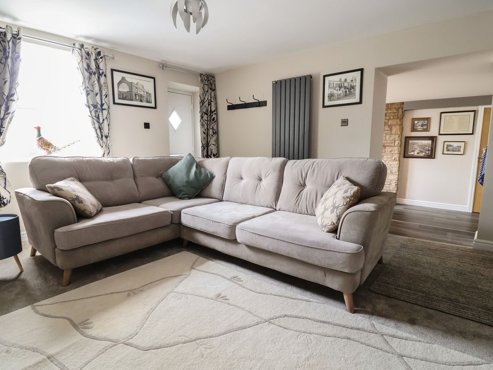 Living room with corner sofa, stove-effect fire and wall-mounted TV