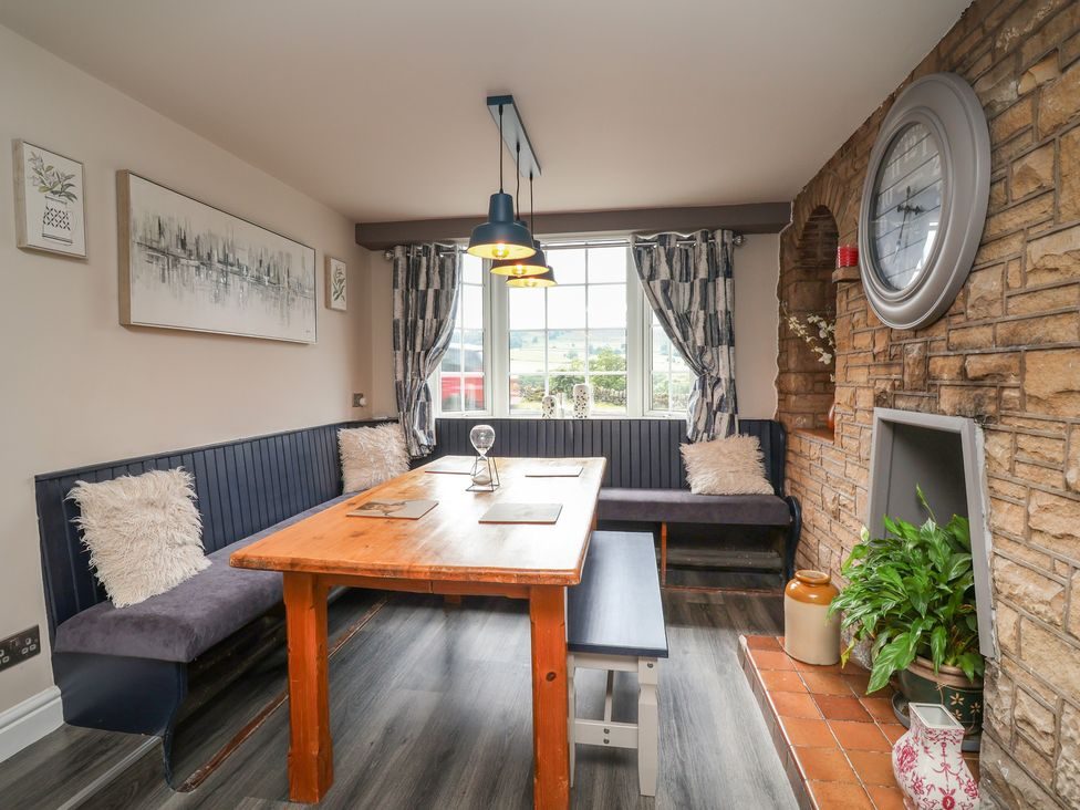 Dining area with wooden table, bench seating, exposed stone wall and a large clock