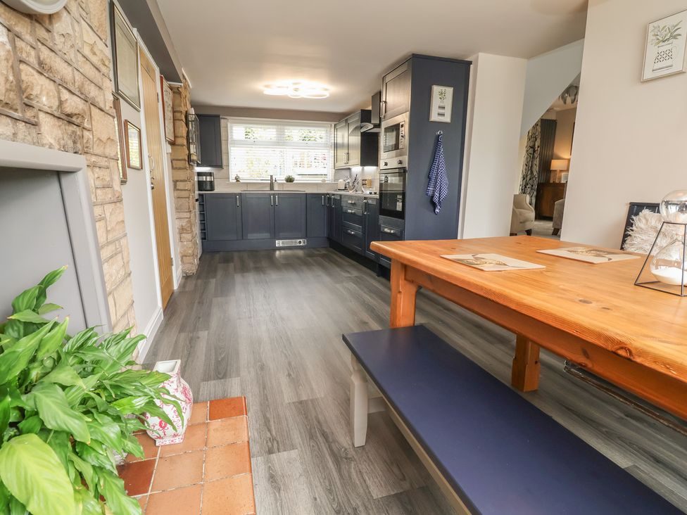 Long wooden dining table with benches, looking through to the kitchen