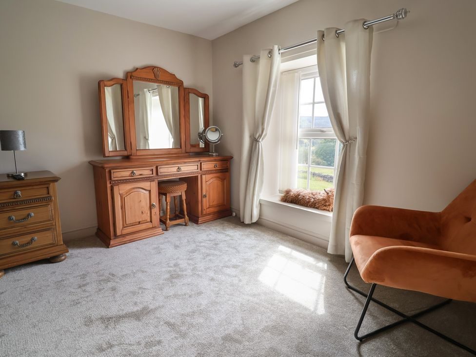 Dressing area in the king bedroom with mirrored dresser and green velvet chair